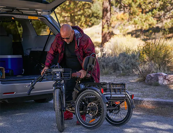 A man unloading a folding electric trike from the back of his vehicle, showcasing the portability and convenience of the e-trike.