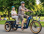 Passenger resting feet on the premium wooden footrest of a tandem trike while the partner pedals.
